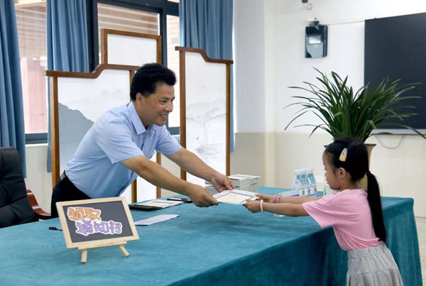 徐龍海用筆在《入學通知書》上認真寫下學生名字，起身將《入學通知書》遞還。金山小學供圖