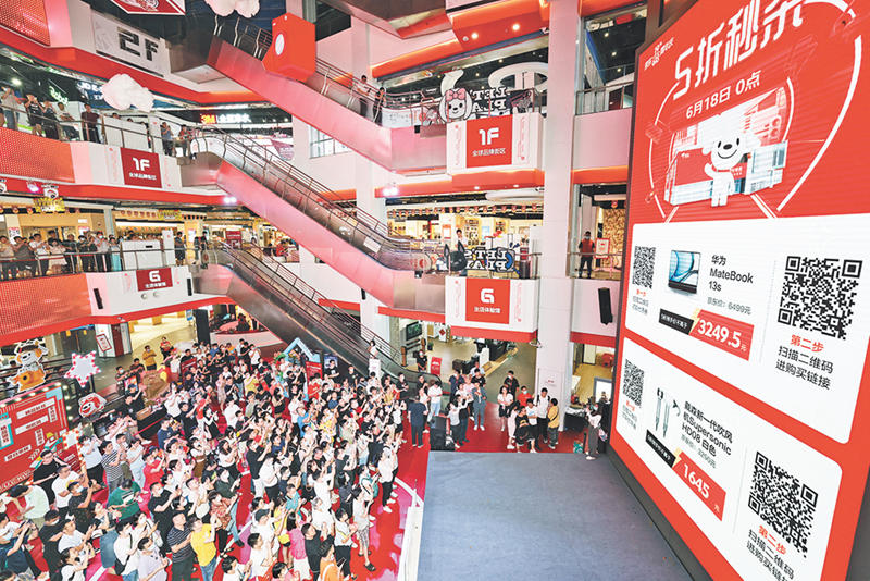 6月18日零時(shí)，寸灘京東超級體驗(yàn)店，消費(fèi)者聚集在大屏幕前，齊舉手機(jī)掃描二維碼，參與京東618電器整點(diǎn)5折秒殺活動。陸綱 攝/視覺重慶