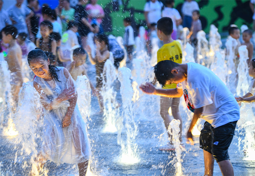 重慶連晴高溫，小朋友在南濱路噴泉下戲水玩耍享受清涼。郭旭攝