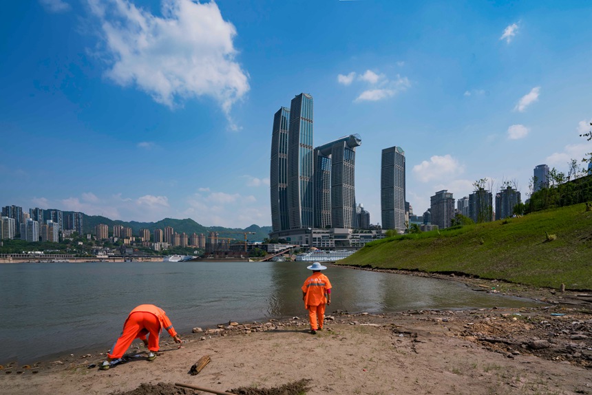 環(huán)衛(wèi)工人冒著烈日清理河邊垃圾。黃進(jìn)攝