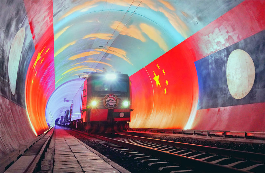 在中國和老撾兩國國旗映襯下，衛(wèi)生列車即將在中老鐵路“友誼隧道”內(nèi)跨越中老兩國邊境。凱喬攝