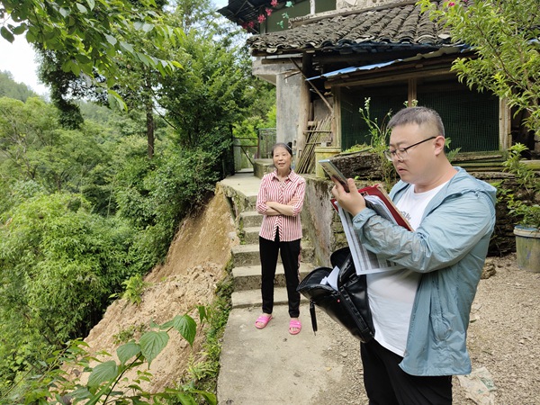 《群眾安全無(wú)小事》。6月15日，黔江區(qū)金溪規(guī)劃和自然資源所會(huì)同107地質(zhì)隊(duì)總工路政坤（右）在金溪鎮(zhèn)清水村祝家?guī)r查看農(nóng)戶屋角發(fā)生的局部垮塌險(xiǎn)情，并提出專業(yè)意見。李偉攝