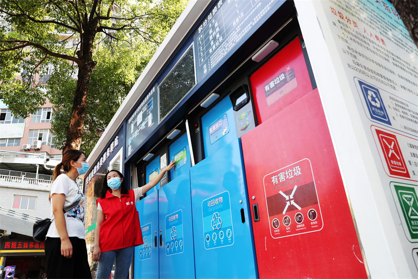 在生活垃圾分類服務(wù)驛站，管理員（右）在給市民講解使用垃圾智能分類的方法。楊敏攝