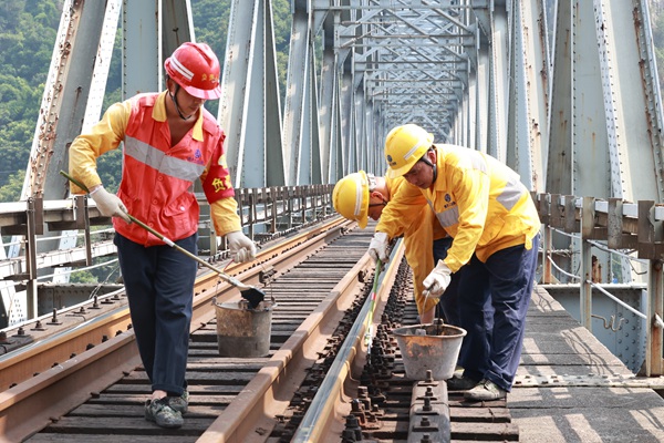 烈日下重慶工電段職工正在對(duì)襄渝鐵路北碚嘉陵江鋼梁大橋枕木扣件螺栓進(jìn)行涂油。晏濤攝