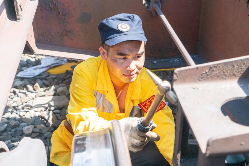 8月9日，重慶西車輛段貨車檢車員正在檢查中歐班列底部吊架技術(shù)狀態(tài)。劉彪攝