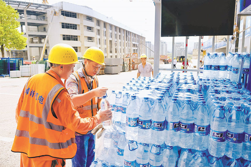 8月15日，南岸區(qū)廣陽灣智創(chuàng)生態(tài)城通江新城中學項目現(xiàn)場，施工人員在項目部補水點領取瓶裝飲用水。特約攝影 郭旭/視覺重慶
