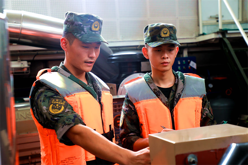 老兵為戰(zhàn)友講解船艇機器參數(shù)。錢云星攝