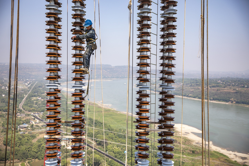 9月13日，在重慶市江津區(qū)白浙線長江大跨越施工現(xiàn)場，施工人員正在攀爬絕緣子串。黃偉攝