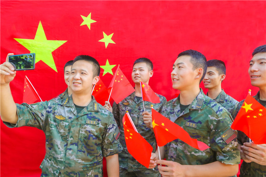 武警官兵與國旗合影，分享國慶喜悅。李東攝