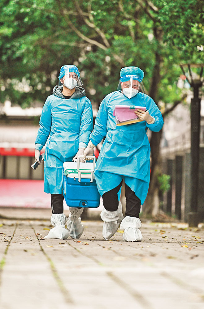 11月17日，北碚區(qū)朝陽街道河嘉村社區(qū)，“95后”志愿者何鑫(右)與張震在轉運核酸樣本。記者 萬難 攝 視覺重慶