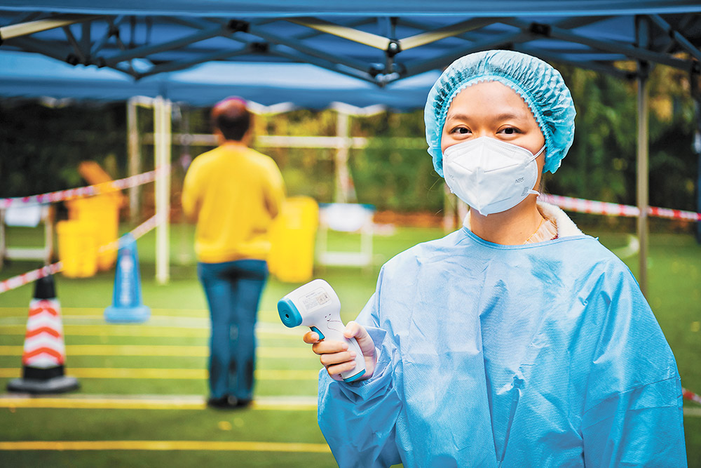 11月17日，綦江區(qū)文龍街道半山國際小區(qū)檢測點，“95后”志愿者劉柳吟為前來核酸采樣的居民測量體溫。特約攝影 陳星宇 視覺重慶