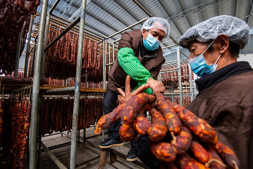 村民在寒冷中晾曬臘腸。?冉孟軍攝