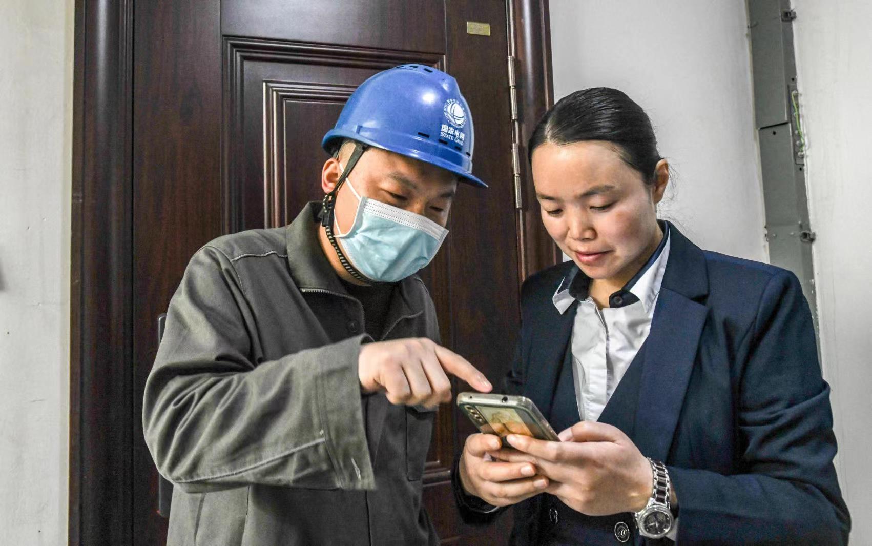 國網(wǎng)江津區(qū)供電公司員工向客戶講解二維碼的用途。王化全  攝