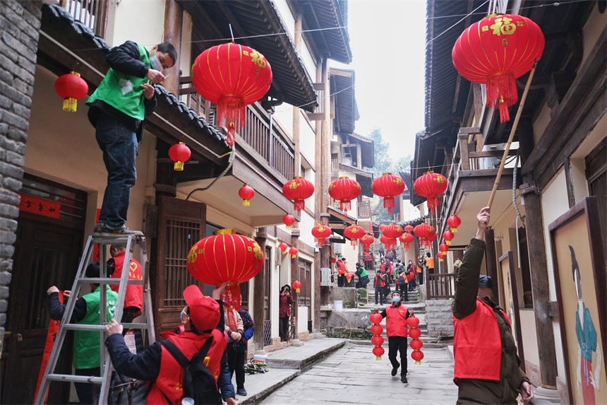 志愿者們正在為黃葛古道敦厚坡段的傳統(tǒng)民居掛燈籠。郭旭攝