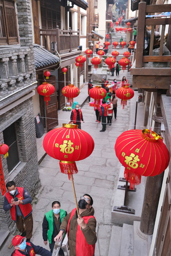 志愿者們正在為黃葛古道敦厚坡段的傳統(tǒng)民居貼春聯(lián)，掛燈籠。郭旭攝