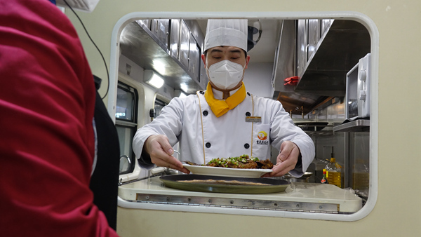 嚴鴻運端上做好的菜。李文航攝