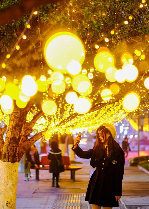 市民在流光溢彩的彩燈前留影。郭旭攝