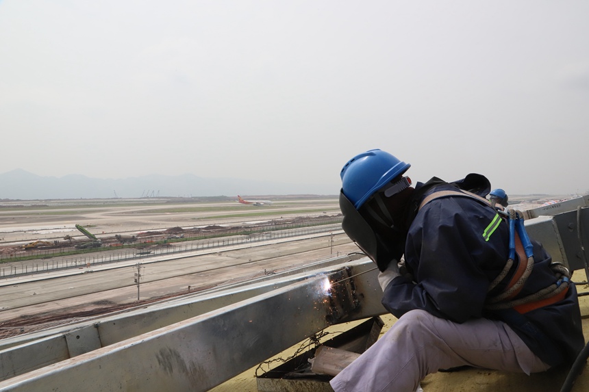 4月29日，工作人員在重慶江北國際機場T3B航站樓施工現(xiàn)場進行屋面施工。中建八局供圖