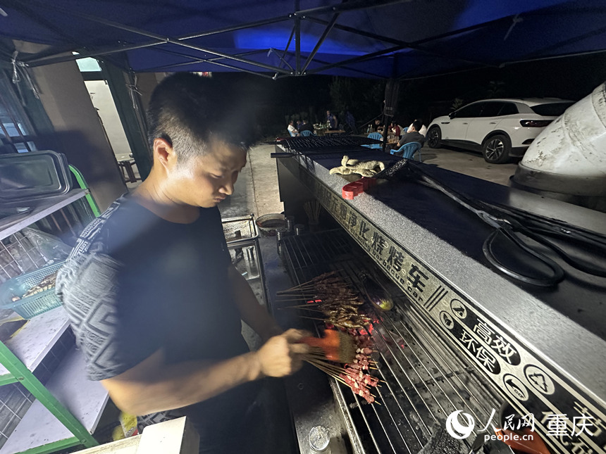 夜晚，方俊在農(nóng)家樂為游客提供燒烤服務(wù)。 人民網(wǎng)記者 劉政寧攝