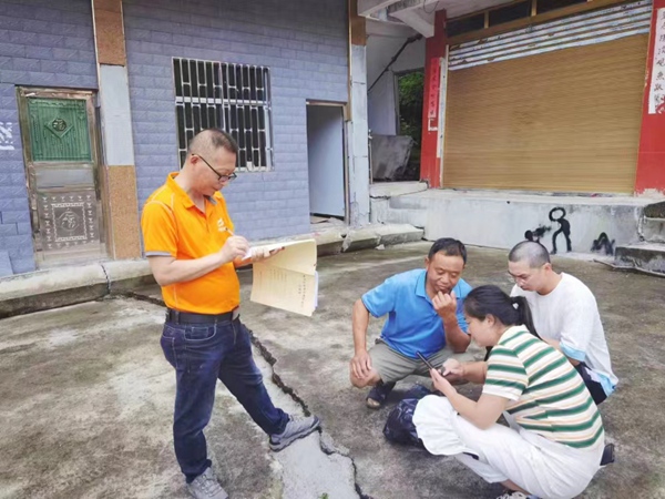 《現(xiàn)場指導(dǎo)》。7月19日，川東南勘察公司酉陽駐守地質(zhì)工程師何登成（左一）在酉陽縣官清鄉(xiāng)百步巖滑坡查看群測群防記錄本，并指導(dǎo)監(jiān)測人員進(jìn)行監(jiān)測工作。牛光猛攝