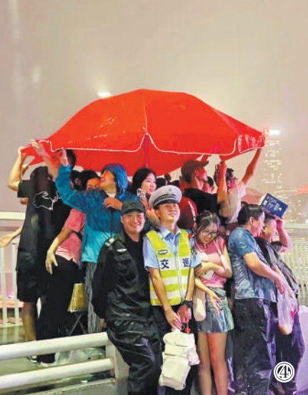 重慶市公安局江北區(qū)分局交巡警支隊(duì)輔警夏英柯在執(zhí)勤中偶遇暴雨，與市民、游客一同避雨。重慶市公安局江北區(qū)分局供圖