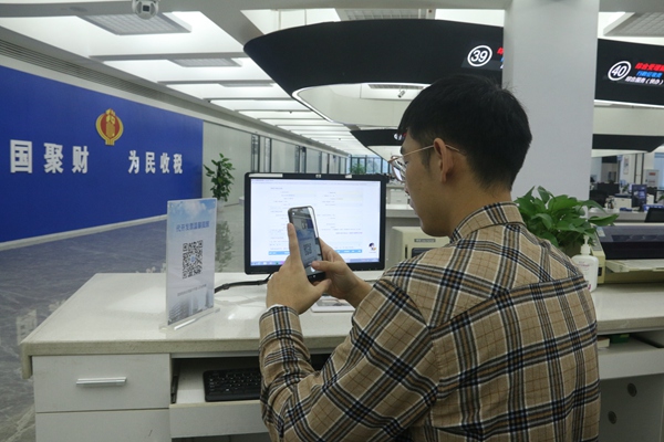 在璧山區(qū)辦稅服務(wù)廳自助辦稅區(qū)，納稅人正在掃描“代開發(fā)票稅率表”二維碼。梅渝攝