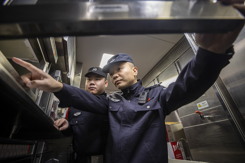 彭聰（右一）在乘警的配合下，對列車電器設(shè)備進(jìn)行檢查。胡勇攝