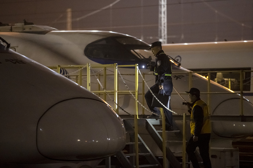 彭聰（左一）在重慶北動車所工作人員的配合下，爬上工作梯，對停放在存車場的列車進(jìn)行巡視。胡勇攝