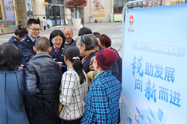 近日，在城口縣名豪廣場(chǎng)，稅務(wù)人員為群眾發(fā)放社保宣傳手冊(cè)。重慶市稅務(wù)局供圖