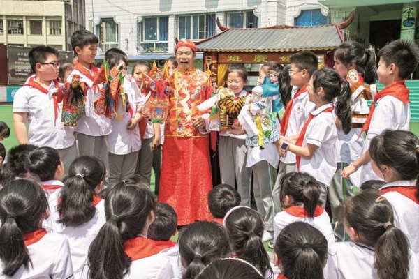 非遺傳承人張賢光給學(xué)生講解手掌木偶戲表演技藝。廣安區(qū)融媒體中心供圖