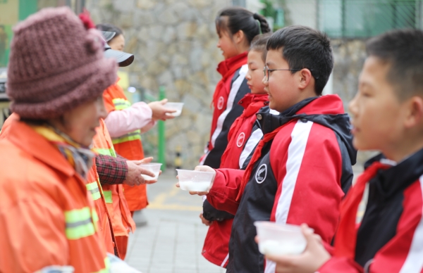 學(xué)生志愿者為社區(qū)清潔工送元宵節(jié)湯圓。九龍坡區(qū)火炬小學(xué)供圖