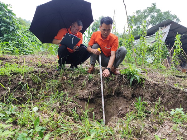 《調(diào)查入微》。6月26日，107地質(zhì)隊(duì)駐守豐都地質(zhì)工程師李?。ㄓ遥⒉逃揽?duì)雷教滑坡地裂縫下挫深度進(jìn)行測(cè)量。李明亮攝