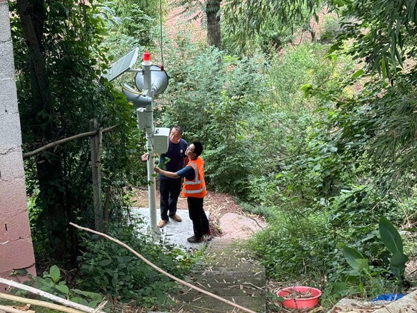 《人防+技防 防災(zāi)更穩(wěn)當(dāng)》。6月24日，巫山縣銅鼓鎮(zhèn)副鎮(zhèn)長劉勇（左）、地質(zhì)駐守隊員王忠凌到竹園村劉家老屋滑坡點，檢查新安裝的地質(zhì)災(zāi)害監(jiān)測設(shè)備運(yùn)行是否正常。人防+技防，才讓地質(zhì)災(zāi)害防治工作更加踏實穩(wěn)妥。謝清艮攝