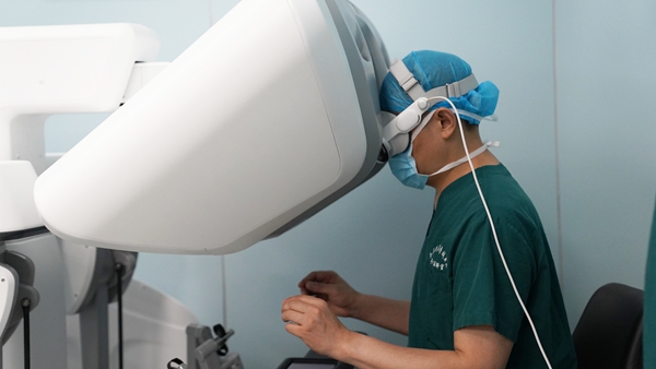 譚群友頭戴空間計(jì)算裝備，操作機(jī)器人進(jìn)行手術(shù)。重慶醫(yī)科大學(xué)附屬大學(xué)城醫(yī)院供圖