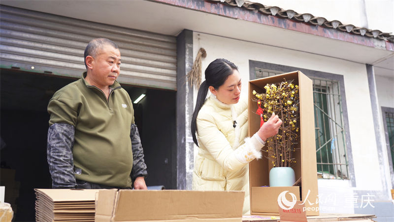 鄧紀(jì)會(huì)正在檢查制作完成的蠟梅花束。人民網(wǎng)記者 劉祎攝