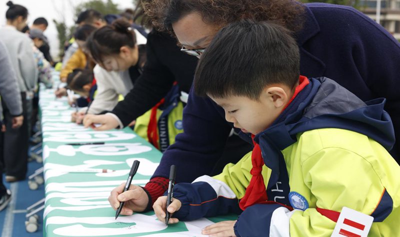學(xué)生和家長在綠色橫幅上寫下祝福語。北碚區(qū)兩江春暉小學(xué)供圖