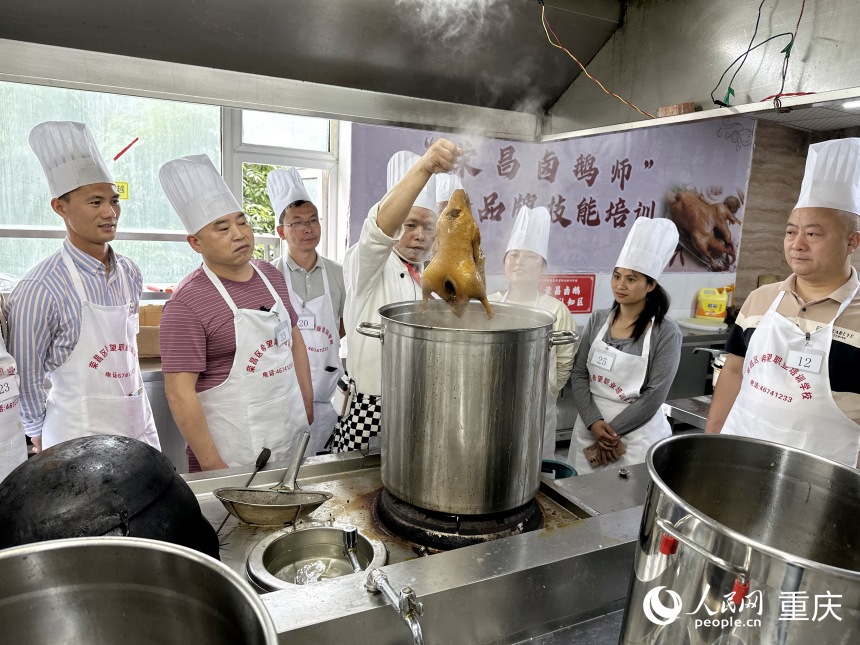 唐春暉（右三）和培訓(xùn)班學(xué)員學(xué)習(xí)傳統(tǒng)鹵鵝制作技藝。人民網(wǎng)記者 劉政寧攝