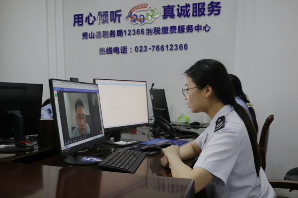 在秀山縣稅務局12366納稅繳費服務中心，稅務人員正通過虛擬窗口與企業(yè)辦稅人員視頻連線，辦理跨區(qū)域涉稅業(yè)務。張雯惠攝