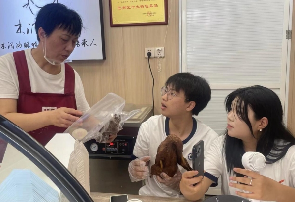 店內(nèi)負(fù)責(zé)人向直播間觀眾展示改良包裝。重慶財經(jīng)學(xué)院供圖