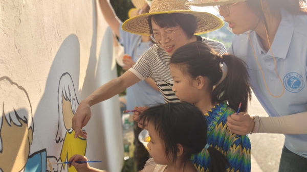 實踐團師生指導小朋友參與繪制法治墻。重慶理工大學供圖
