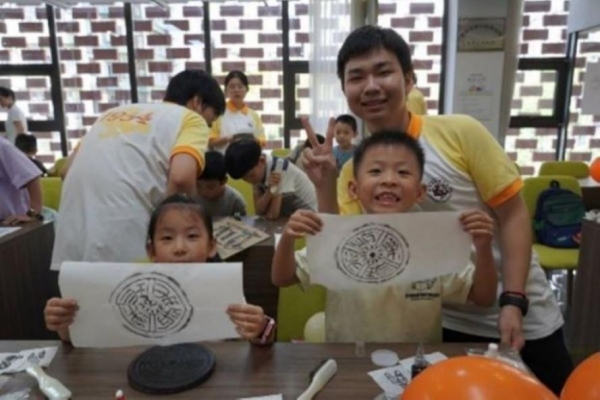 團(tuán)隊(duì)成員指導(dǎo)小朋友體驗(yàn)拓印。重慶師范大學(xué)供圖