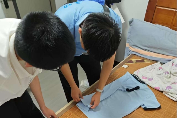 志愿者指導(dǎo)小朋友整理衣物。重慶理工大學(xué)供圖