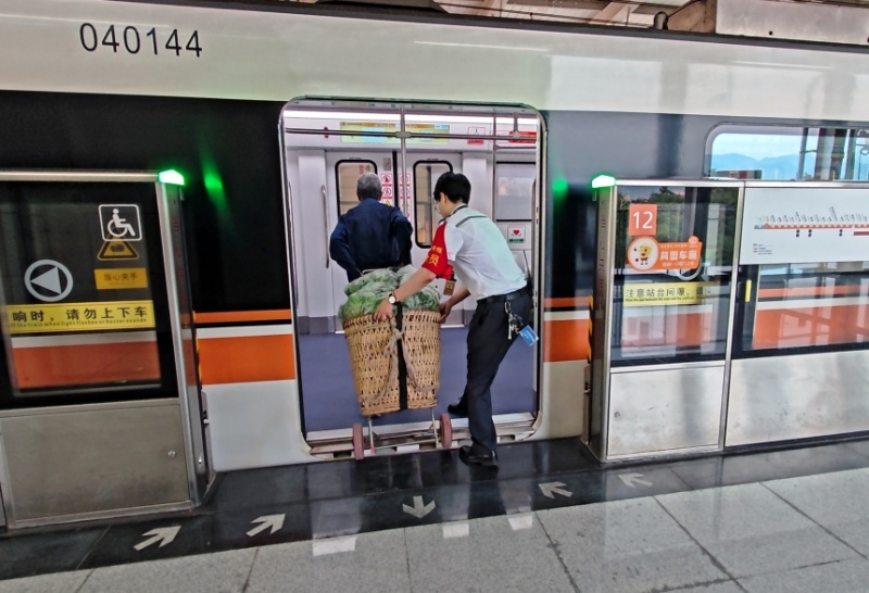 工作人員幫菜農(nóng)將背簍運(yùn)進(jìn)地鐵車廂。重慶軌道四號線建設(shè)運(yùn)營有限公司供圖