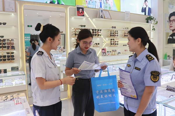 在綦江區(qū)萬達商圈，稅務人員走訪商圈內的店鋪，宣傳講解稅法條款。任韻西攝