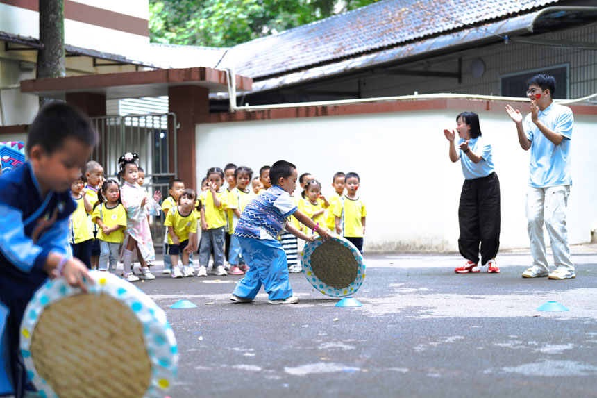 兒童們體驗壯族滾簸箕。劉宇飛攝