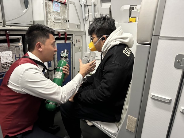 機(jī)上乘務(wù)員向旅客實施吸氧救助。重慶航空供圖