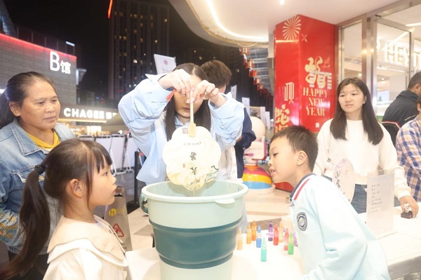 年輕市民用印有中醫(yī)藥文化知識的紙扇體驗漆扇制作。曾英豪攝