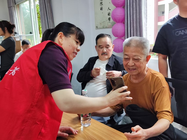 志愿者在幫助老年人使用數(shù)字關愛平臺。受訪者供圖