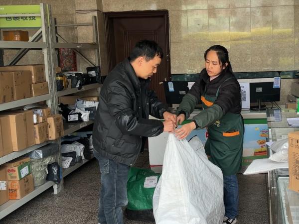 公交車司機(jī)將貨物交接給雙壩村綜合便民服務(wù)站人員。渝運(yùn)集團(tuán)萬盛分公司供圖